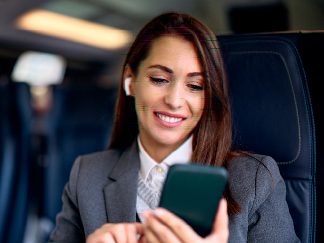 Viajera en un avión consultando el móvil. Algunas partes de su cara están con una lineas horizontales verdes dando a entender que el móvil está escaneando su cara