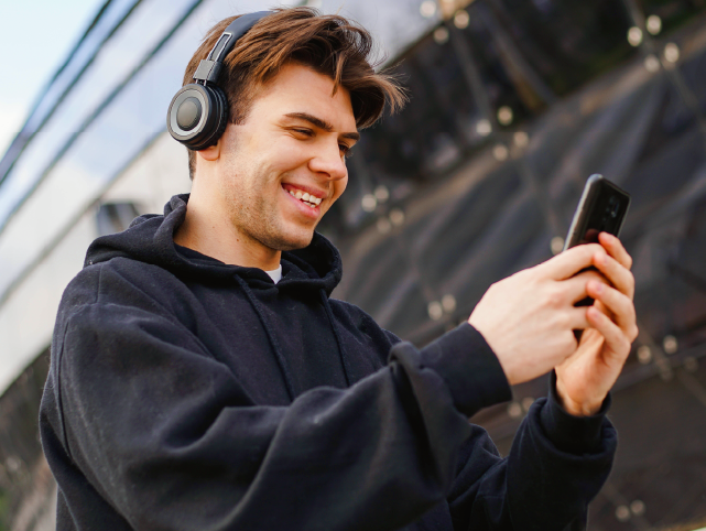 Joven con cascos mirando el teléfono móvil