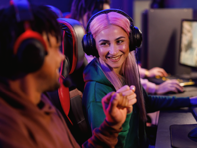 Dos gamers, chica y chico, chocan sonrientes