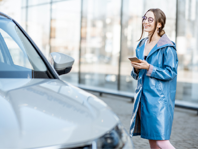 Usuaria frente al coche con el móvil en la mano