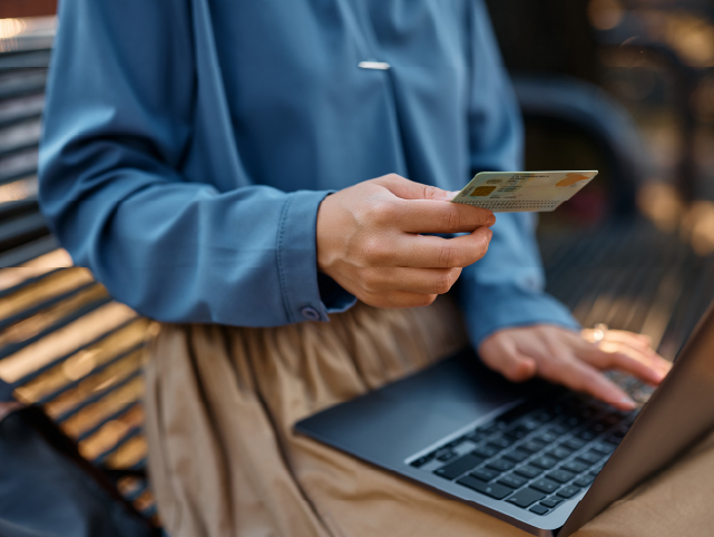 Detalle de tronco de usuario. En una mano tiene un DNI con la otra está escribiendo en un portátil