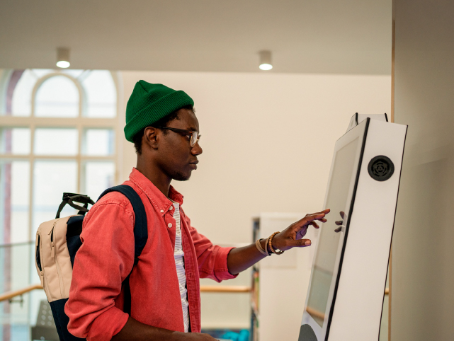 Joven usando una pantalla táctil en lo que podría ser un hospital