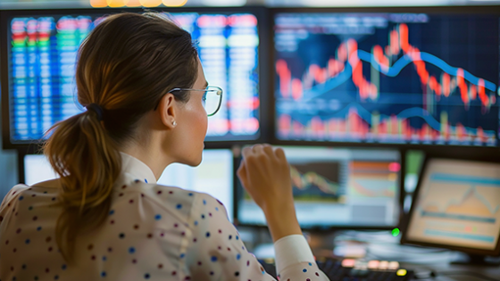 Mujer mirando varias pantallas con información financiera