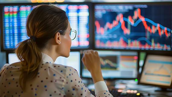 Mujer mirando varias pantallas con información financiera