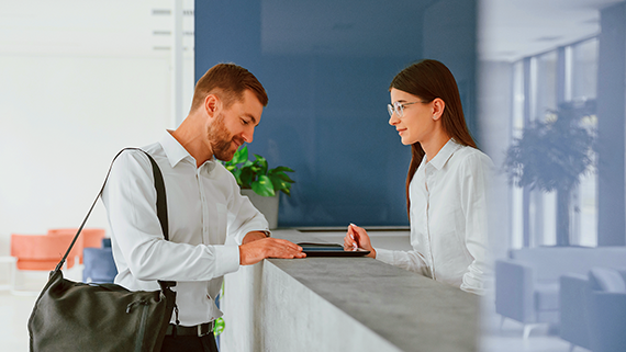 Un hombre hace el checking en un hotel frente a la recepcionista