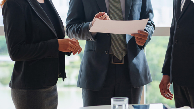 Group of executives holding a document, partially visible faces out of frame