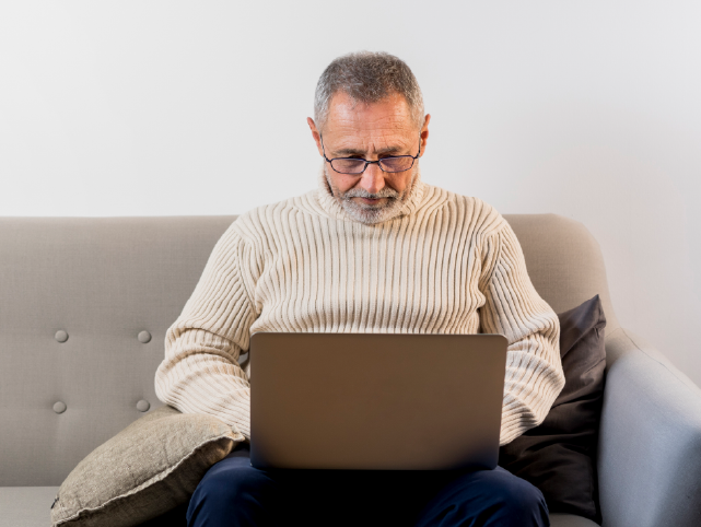 Hombre sentado en el sofá utilizando el portátil