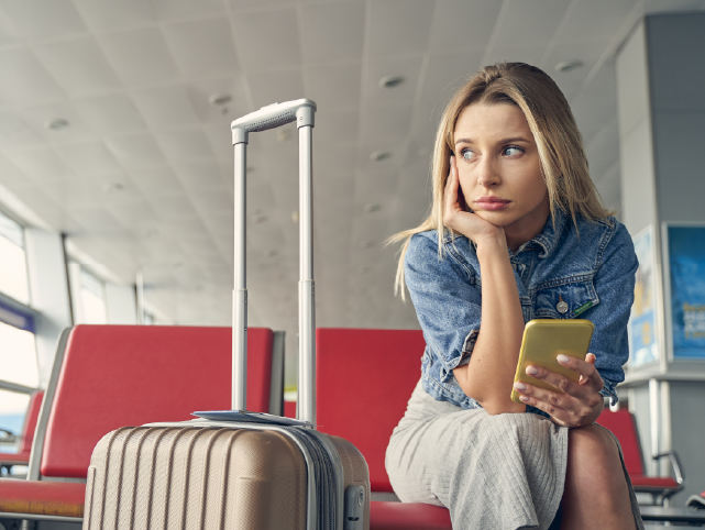 Viajera, aparentemente aburrida, junto a su maleta