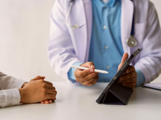 Un médico muestra a un paciente su historial medico en una tablet