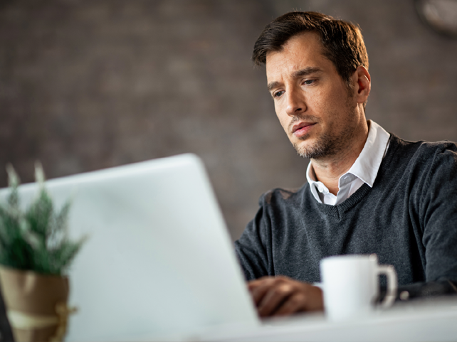 Usuario trabajando frente a su portátil y taza de café